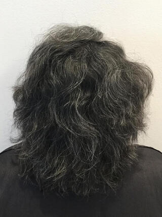 Photo avant : vue arrière d'une femme aux cheveux noirs courts avec beaucoup de cheveux blancs avant la couleur.
