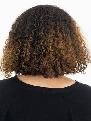 Photo avant : vue arrière d'une femme aux cheveux noirs courts et bouclés avec des racines développées avant la coloration.